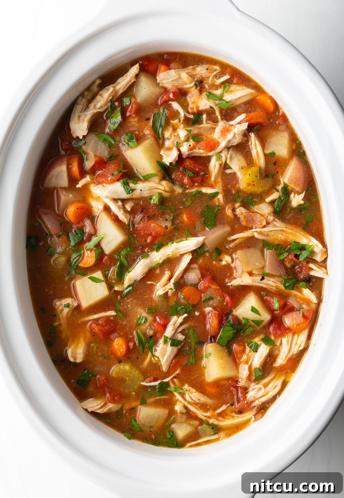 Soul-Satisfying Slow Cooker Chicken Stew 10 Healthy crock pot chicken stew in a white crock pot, ready for serving.