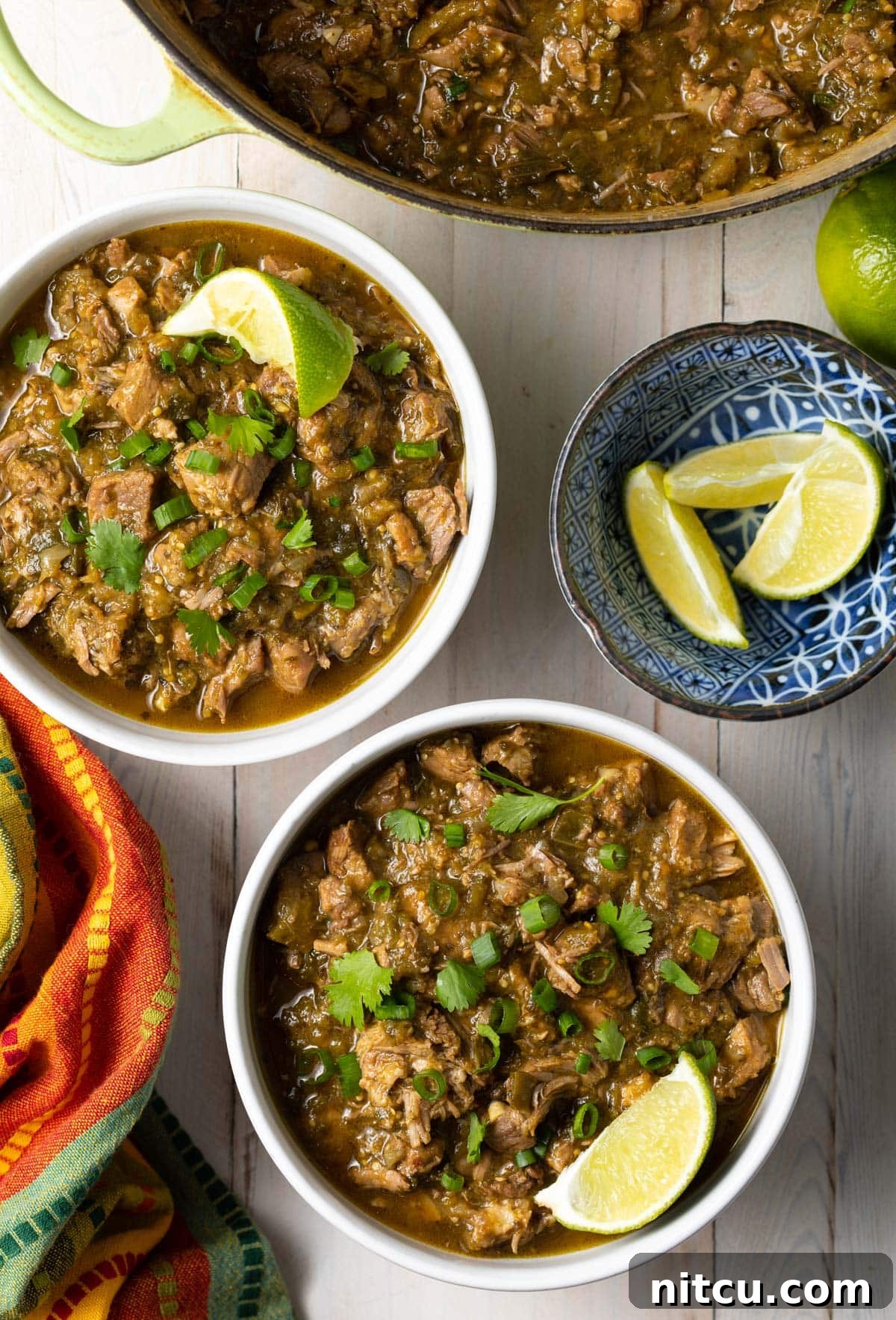 Signature New Mexico Green Chile Stew 4 Two bowls of New Mexican green chile with fresh lime wedges on the side, ready for serving.