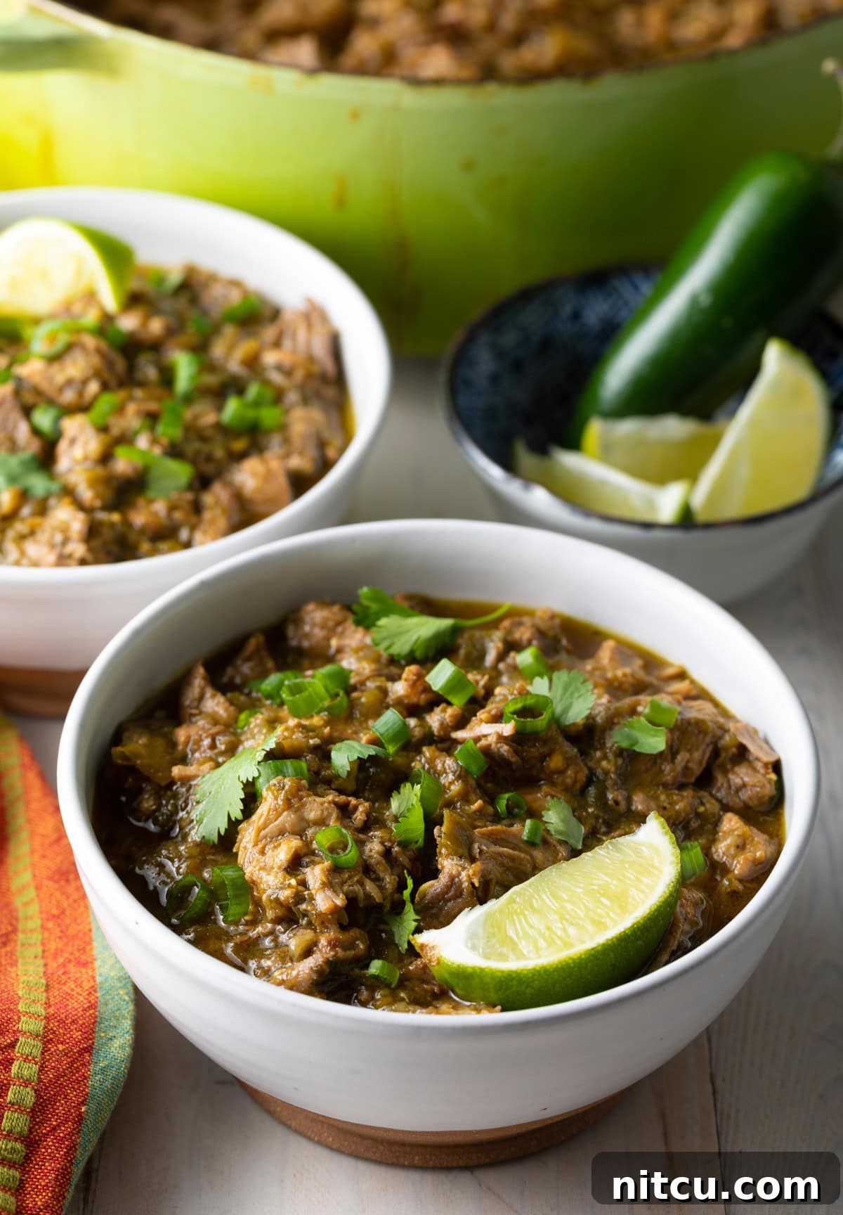 Signature New Mexico Green Chile Stew 9 Two bowls of Green Chili (Chile Verde) adorned with fresh lime wedges, ready to be enjoyed.