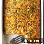 Savory Morning Sausage Bake 14 Pan of egg casserole with sausage and vegetables. A spatula is in the pan, with square portions of the casserole removed.