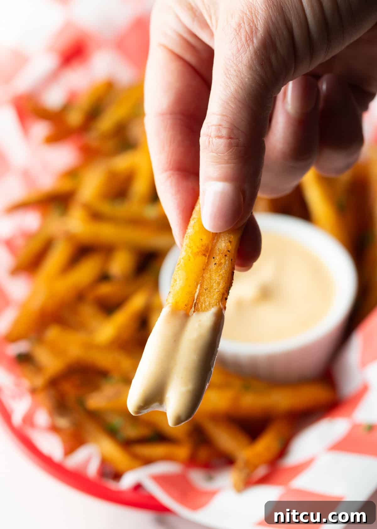 Next-Level Fry Sauces 5 A hand holding two French fries that have been dipped in French fry dipping sauce.