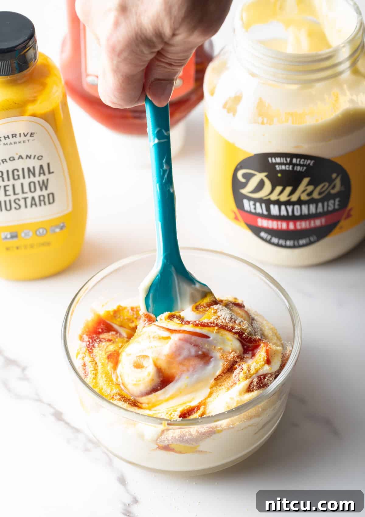Next-Level Fry Sauces 7 A spatula stirring French fry sauce ingredients in a glass bowl.