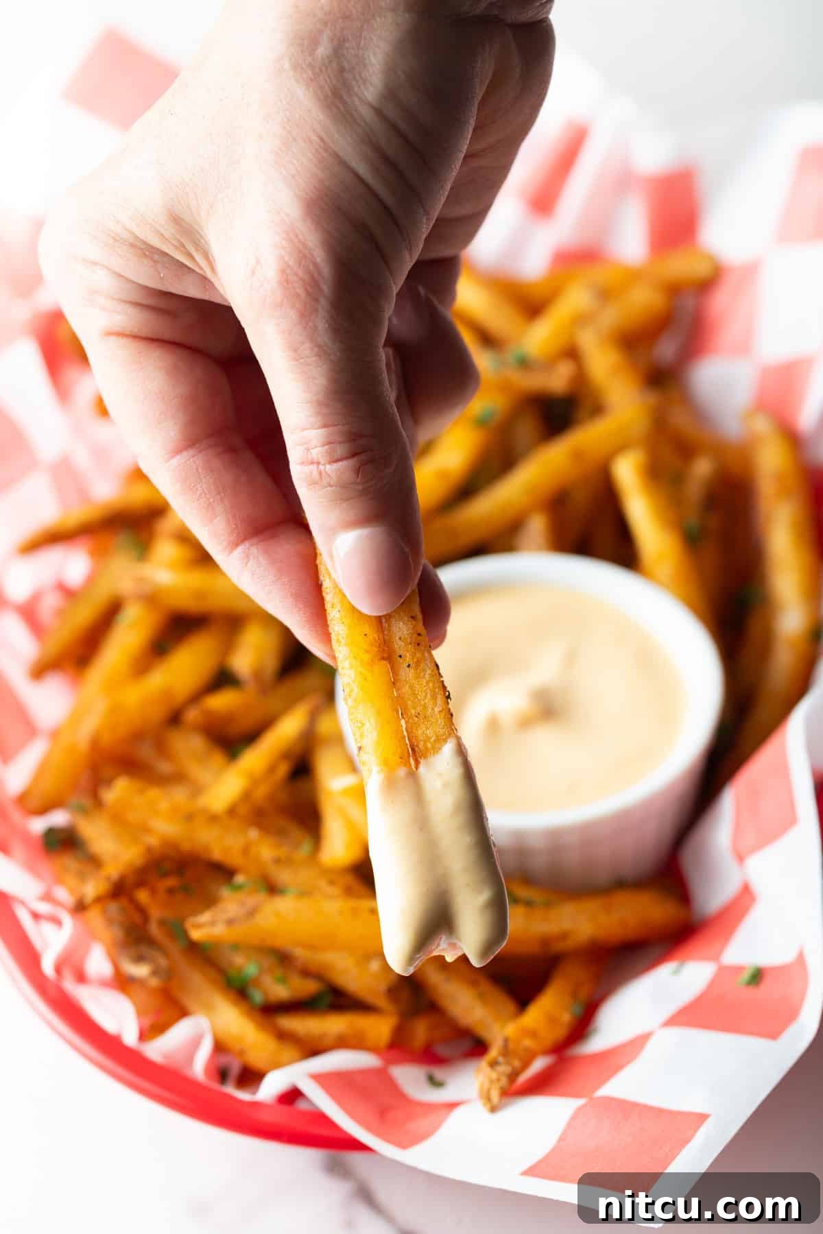 Next-Level Fry Sauces 9 A hand holding two French fries that have been dipped in easy French fry dipping sauce.