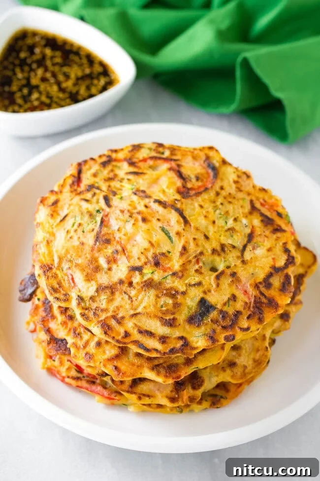 Crispy Pajeon Korean Pancake Recipe A perfectly cooked scallion and vegetable Korean pancake, Pajeon, freshly made and stacked on a plate, ready to be served and enjoyed.