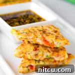 A close-up of a finished Korean pancake (Pajeon) wedge with crispy edges and visible vegetables, ready for serving.