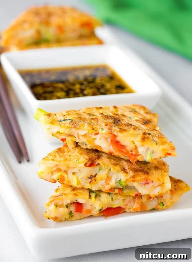 Best Korean Pancake Recipe with Vegetables A close-up inside view of perfectly cooked Korean vegetable pancakes (Pajeon) arranged on a platter, showcasing the vibrant julienned vegetables embedded within the tender, savory batter.