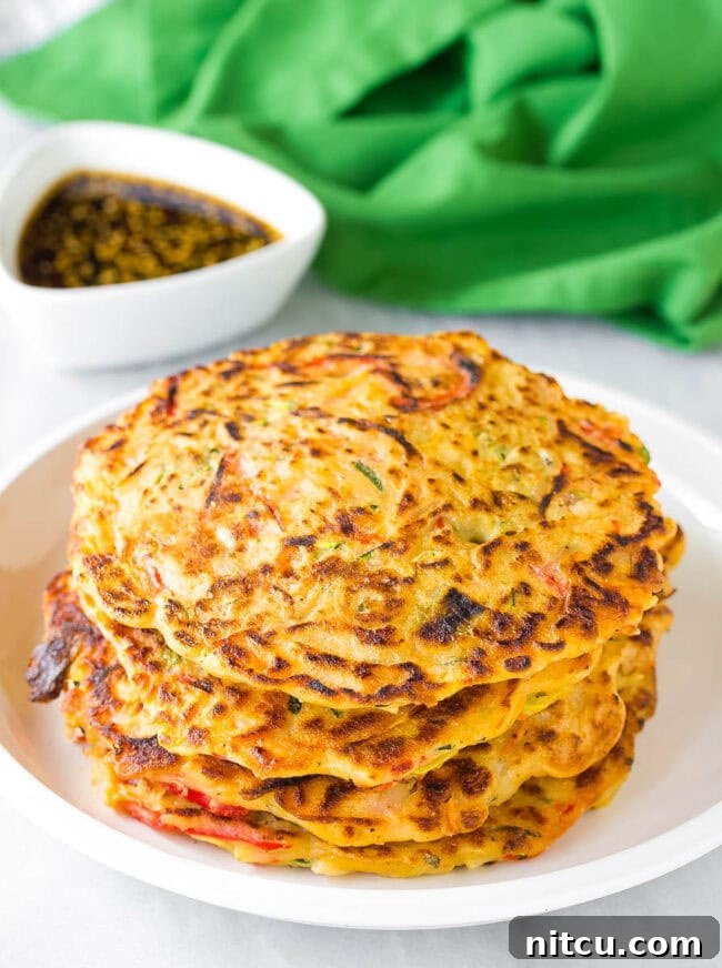 Pajun Savory Korean Pancakes A stack of golden-brown Korean pancakes (Pajeon) resting on a clean white plate, showcasing their inviting crisp texture and fluffy interior.