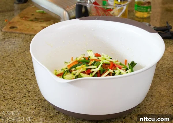 Sizzling Korean Jeon 4 A vibrant bowl filled with perfectly julienned vegetables—carrots, bell peppers, and zucchini—ready to be incorporated into the savory Korean pancake batter.