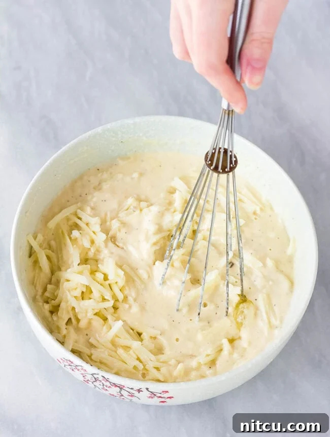 Sizzling Korean Jeon 5 A light-colored, savory Korean pancake batter is being vigorously whisked in a large mixing bowl, creating a smooth and consistent base for the Pajeon.
