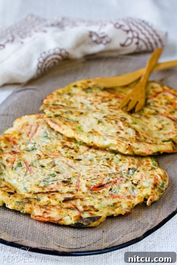 Sizzling Korean Jeon 7 Two freshly fried Korean pancakes are presented side-by-side on a white plate, showcasing their perfect golden crust and inviting texture.