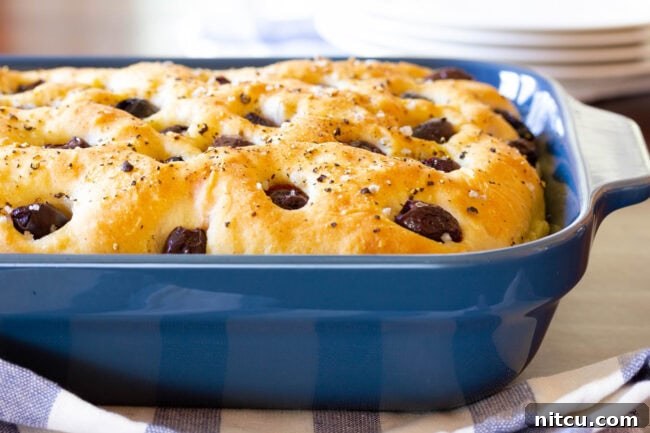 Golden Herb & Olive Focaccia 9 Blue baking dish with roasted garlic and olive focaccia bread.