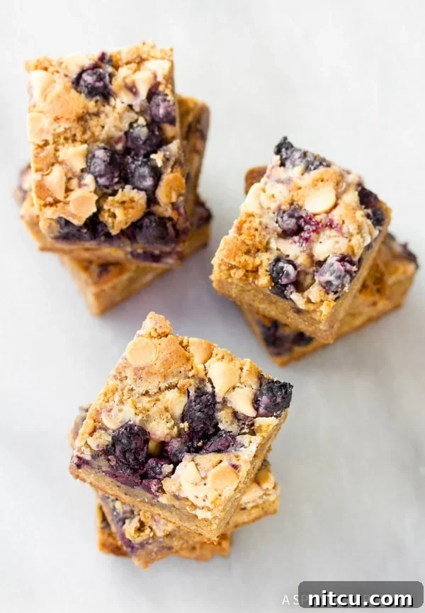 Freshly baked and cut Blueberry White Chocolate Blondies arranged on a serving board.