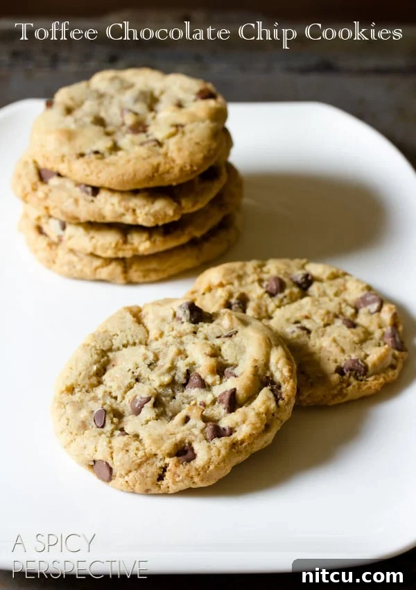 Toffee Chocolate Chip Cookies on plate with cookies stacked in back