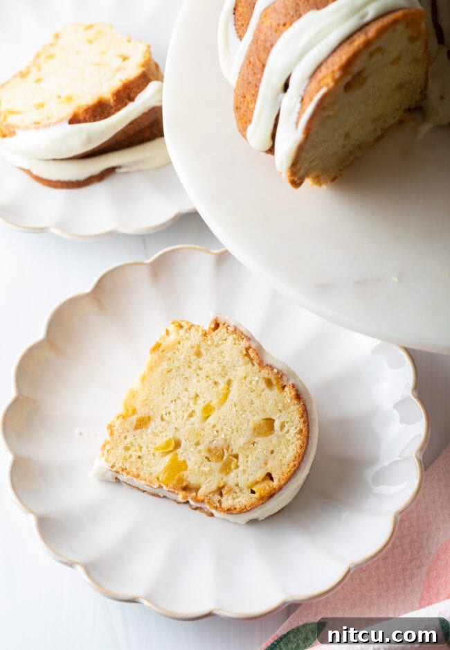 Luscious Peach Bundt Cake 3 Close-up slice of moist peach bundt cake, revealing tender peach chunks, in a bundt pan.