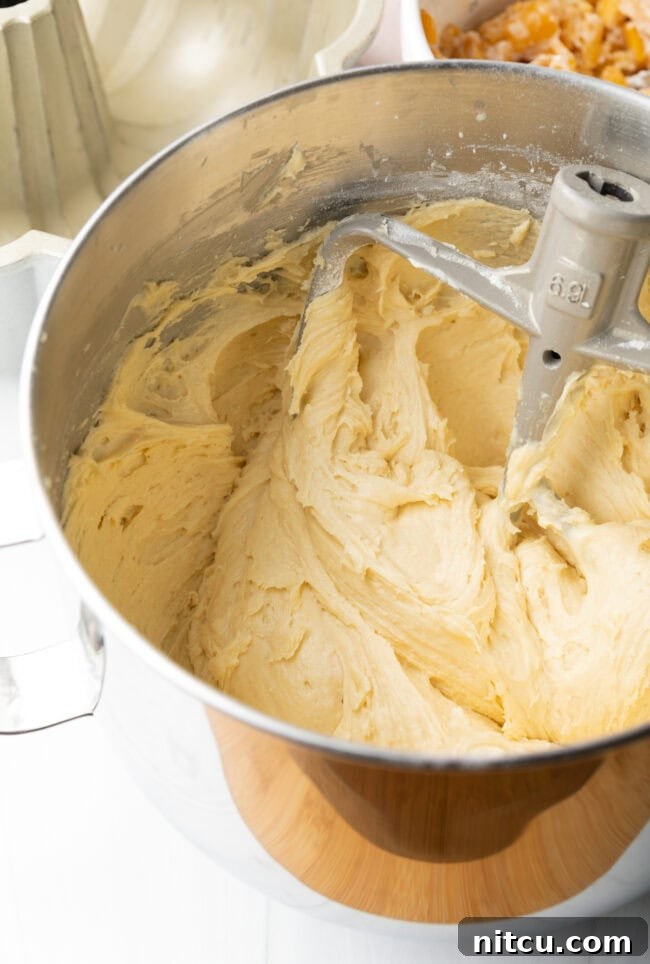 Luscious Peach Bundt Cake 5 Creamy batter being poured into a greased bundt pan, showing the cake preparation.