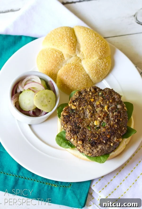 Signature Mediterranean Burger 7 A single Mediterranean burger resting on a plate, showcasing its layers and delicious appearance.