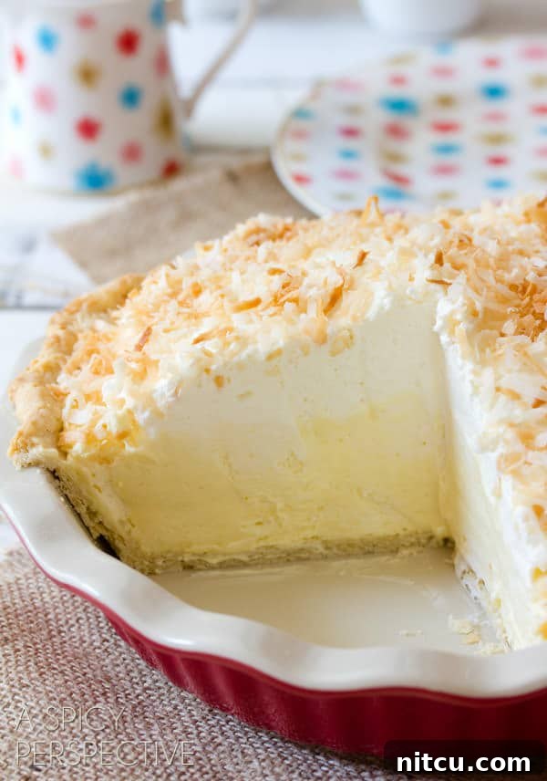 Luscious Coconut Cream Pie Coconut Pie Recipe with Cream of Coconut - whole pie with sliced cut out showing the inside of the thick cream pie