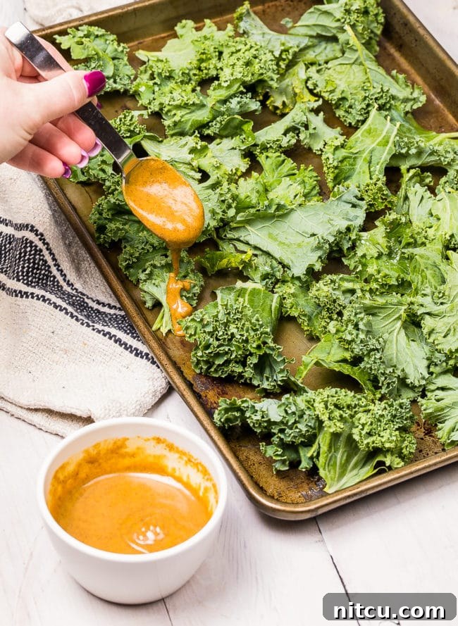 Effortless Crispy Kale Chips 8 Hand pouring butter spice mixture over kale chips.