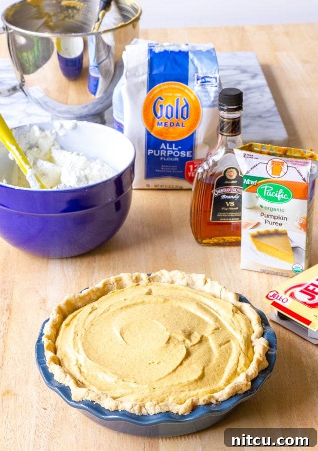 Velvet Pumpkin Cream Pie 3 Individual ingredients like cream cheese, pumpkin puree, and spices arranged for pumpkin cream pie