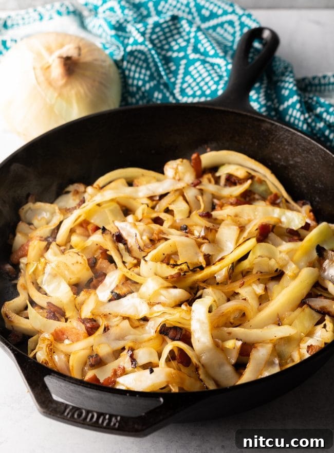 Mixing cooked egg noodles into the sautéed cabbage and bacon for Hungarian Haluski