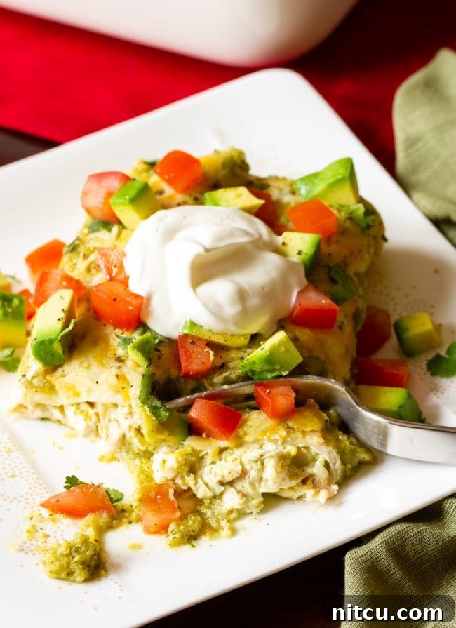 A hand holding a fork, poised to take a bite of the delicious and easy Salsa Verde Chicken Enchiladas Verde.