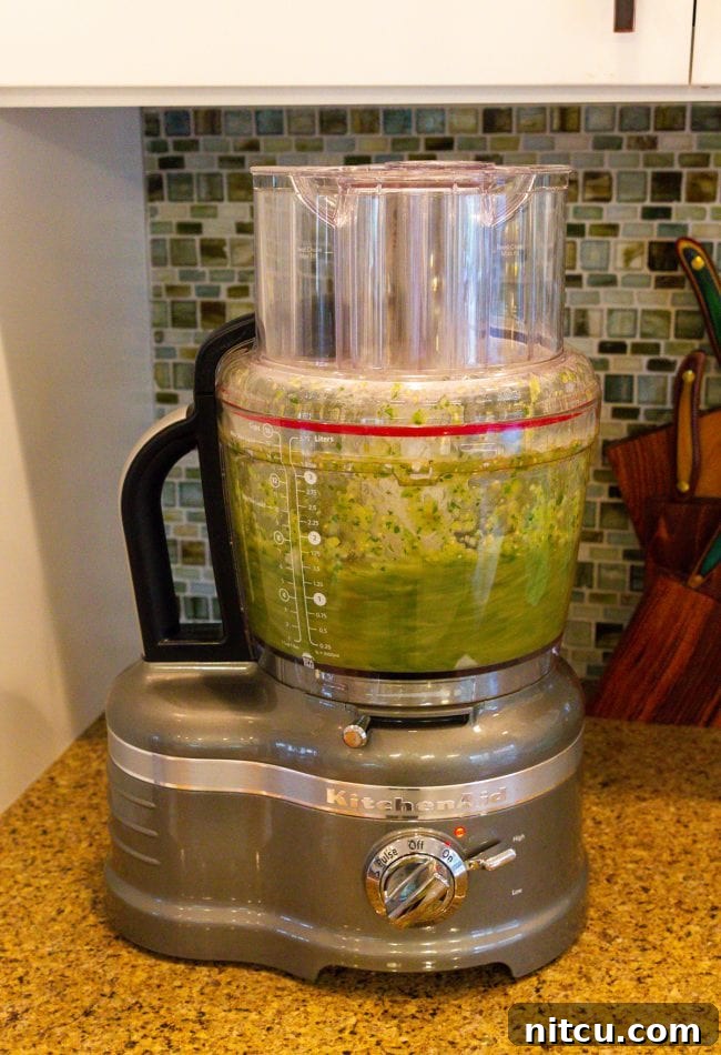 Roasted salsa verde ingredients being blended in a food processor.