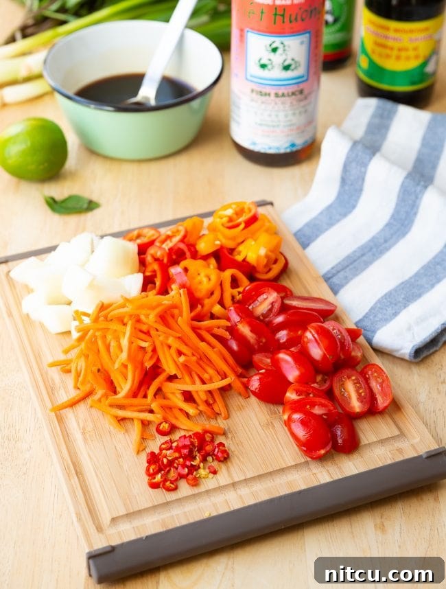 Addictive Pad Kee Mao Drunken Noodles Recipe 4 Freshly chopped and prepared vegetables for Pad Kee Mao laid out on a wooden cutting board, showcasing the vibrant ingredients.