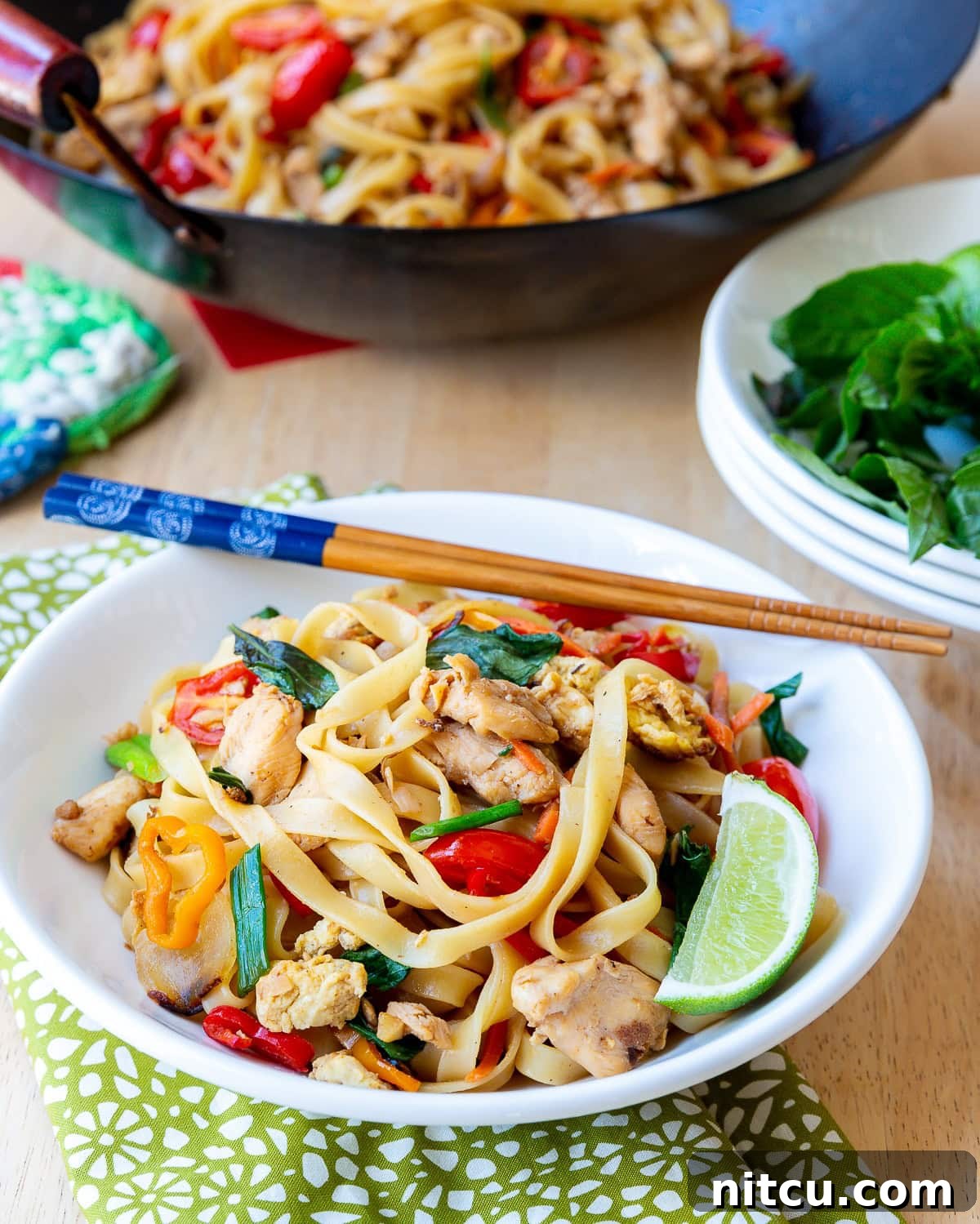 Addictive Pad Kee Mao Drunken Noodles Recipe 6 A beautifully plated bowl of Pad Kee Mao, served with fresh lime and chopsticks, highlighting its vibrant colors and textures.