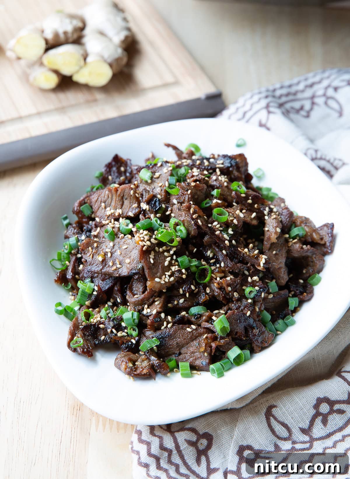 Sizzling Korean BBQ Delights 2 Beef bulgogi served in a white bowl topped with scallions and sesame seeds.