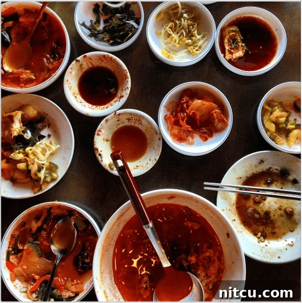 Sizzling Korean BBQ Delights 4 Several half-empty white bowls filled with classic Korean side dishes.