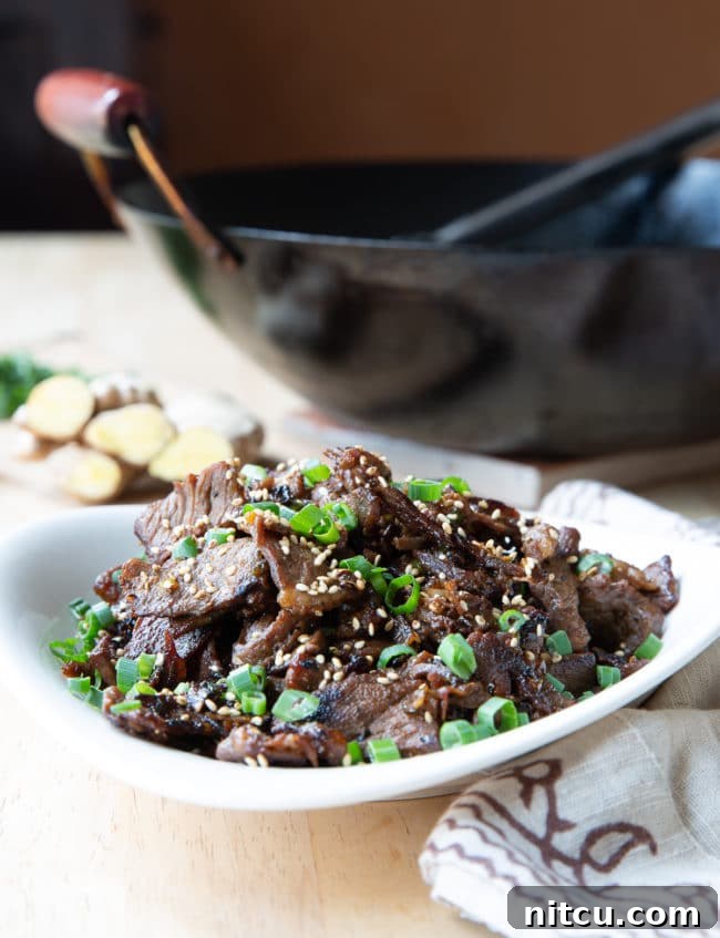 Sizzling Korean BBQ Delights 8 Korean beef bulgogi served in a white bowl with a black wok in the background.