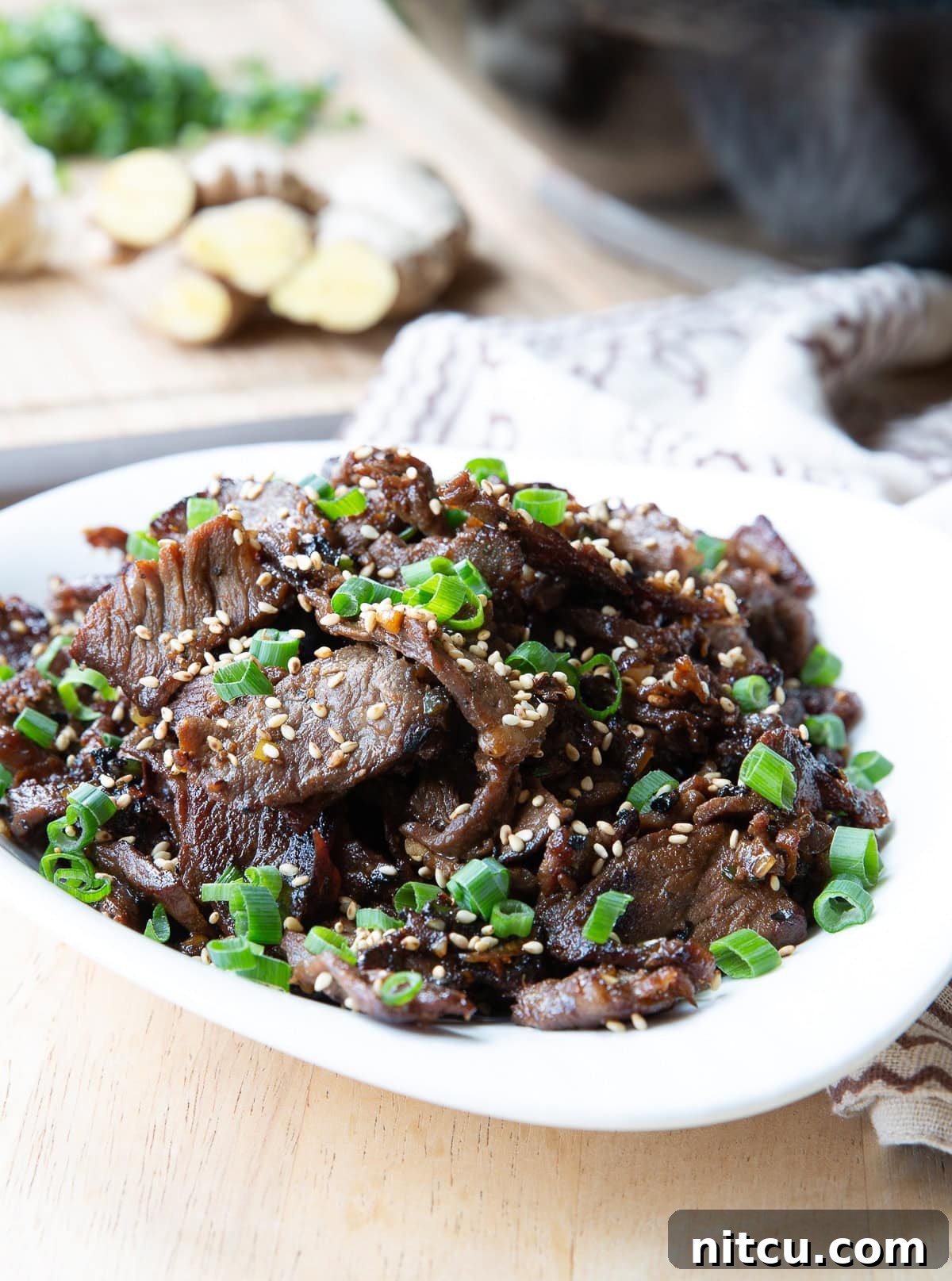 Sizzling Korean BBQ Delights 10 Bulgogi served in a large serving dish topped with sesame seeds and scallions.