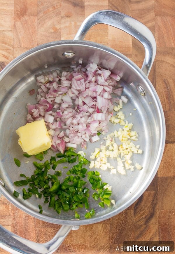 Creamy Homemade Queso 4 Diced jalapenos, shallots, garlic, and butter being sauteed in a pot, releasing fragrant aromas.