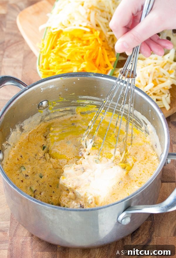 Creamy Homemade Queso 5 Hand whisking softened cream cheese into the simmering queso dip base, creating a smooth mixture.