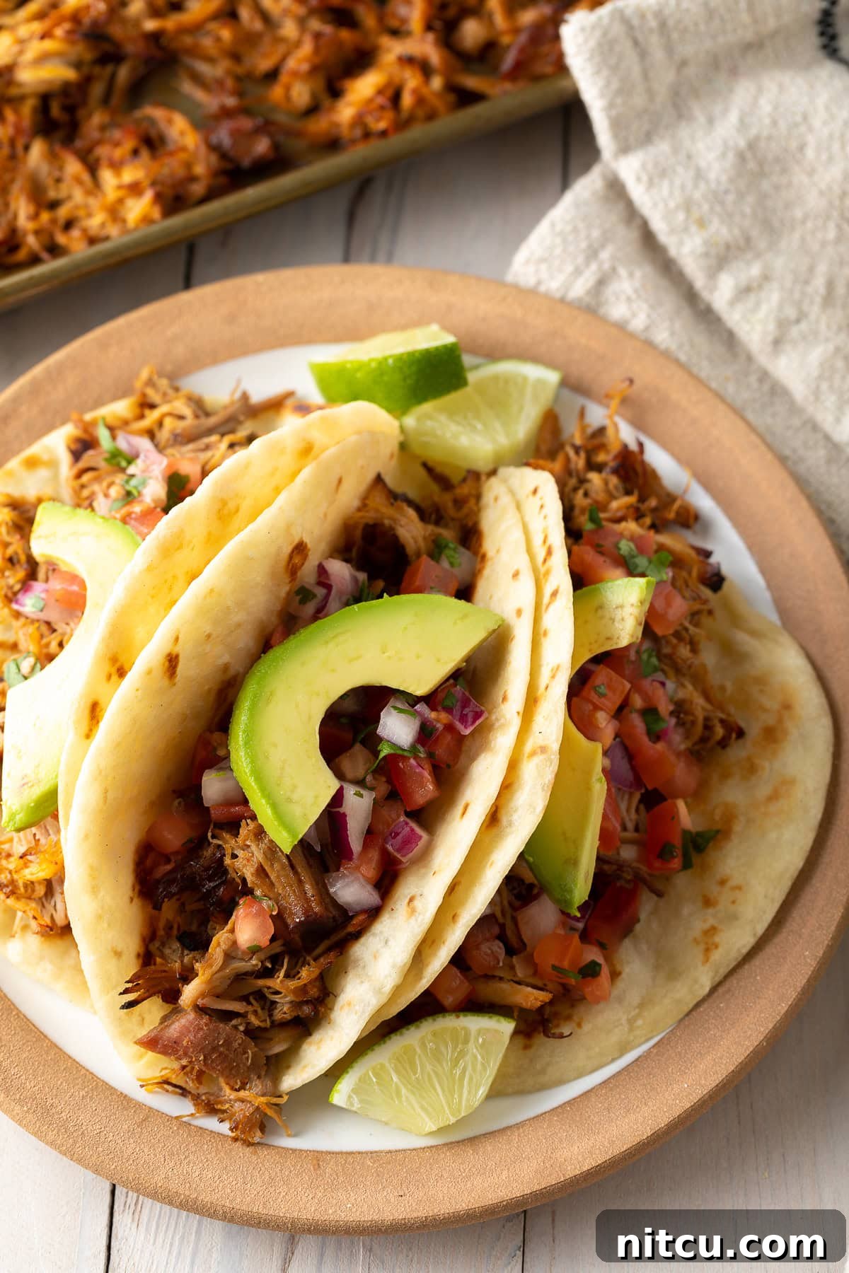 Slow-Cooker-Carnitas-Recipe Delicious carnitas tacos loaded with toppings on a plate, showcasing the tender shredded pork.