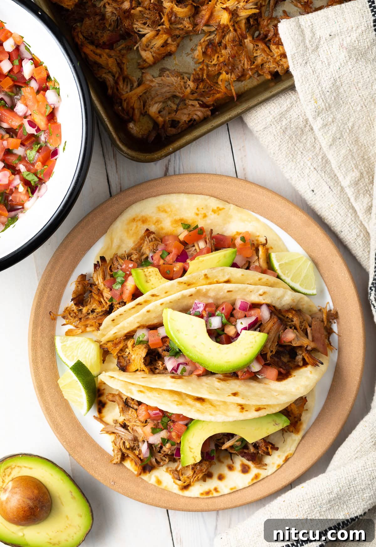 Easy-Slow-Cooker-Carnitas-Recipe An overhead shot of an easy slow cooker carnitas tacos recipe plated beautifully with fresh toppings.