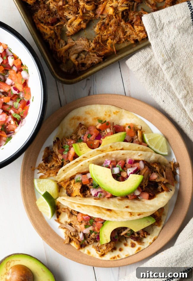 Liquid-Smoke-for-Smoked-Flavoring An overhead shot of plated slow cooker carnitas, garnished with fresh avocado slices and lime wedges, ready to be served.
