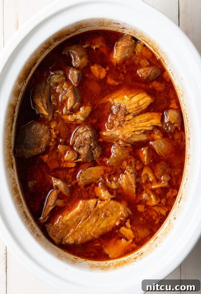Crispy Pork Carnitas Made Easy 5 Pork carnitas after hours of slow cooking, appearing incredibly tender and juicy in the pot.
