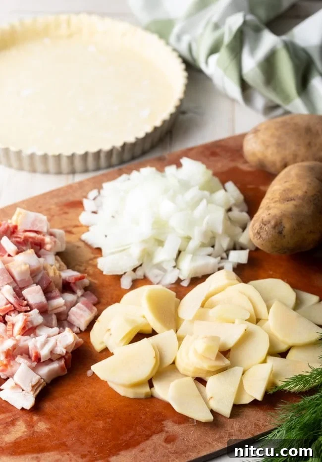 Emerald Spud Pie 3 Various ingredients laid out on a kitchen counter, including puff pastry, potatoes, bacon, and herbs, ready for assembling the potato pie.