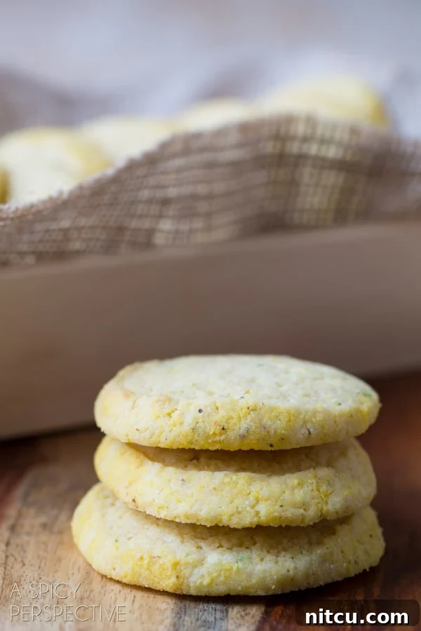 Sun-Kissed Cornmeal Treats 4 Soft Cornmeal Cookies stacked on a counter with a baking dish in the background, highlighting their homemade appeal.