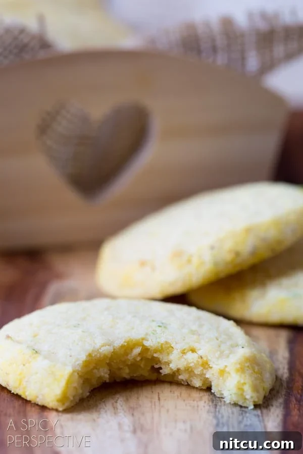 Sun-Kissed Cornmeal Treats 5 Closeup of a cornmeal cookie with a bite removed, revealing its tender interior and speckles of lime zest.