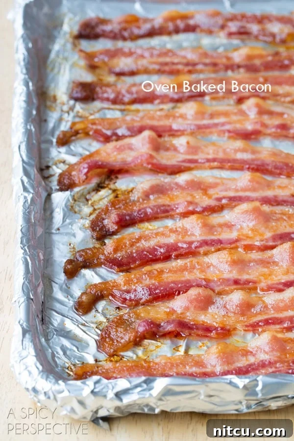 Perfectly cooked, crispy bacon slices on a parchment-lined baking sheet, freshly removed from the oven and ready to be enjoyed. #ASpicyPerspective #BaconinTheOven #Bacon #Oven #BakingBacon #HowtoCookBaconinTheOven #CookingBaconintheOven #HowtoBakeBacon #OvenBakedBacon #CrispyBacon #EasyBacon