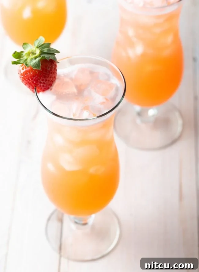 Crafting Refreshing Agua Fresca 7 3 tall cocktail beverage glasses filled with strawberry pineapple agua fresca. Each class is garnished with a strawberry on the rim.
