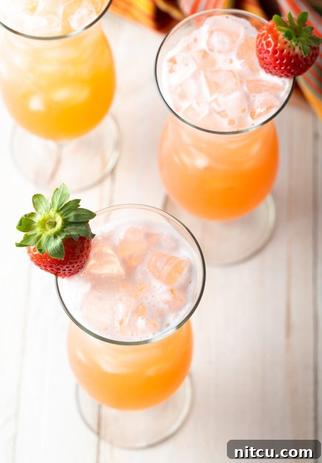 Crafting Refreshing Agua Fresca 8 Top down view 3 tall hurricane glasses with authentic aguas frescas, each garnished with a whole strawberry.