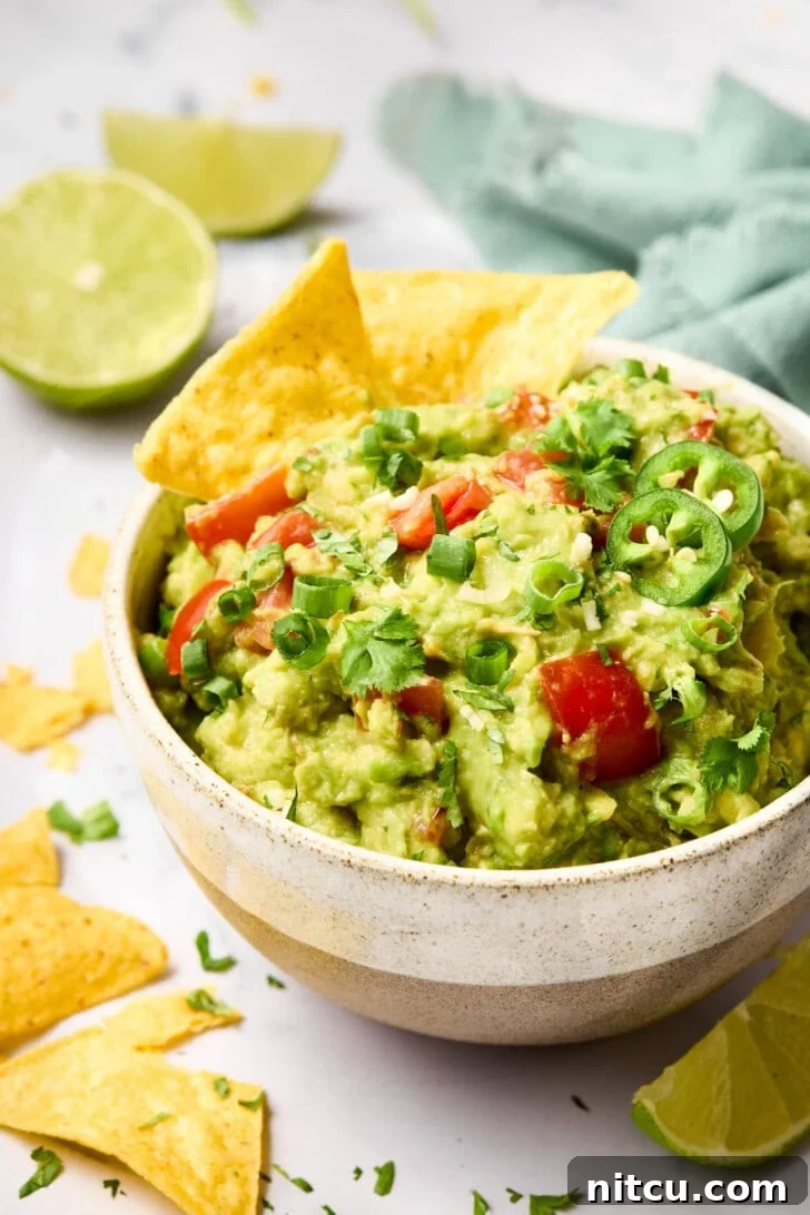 Heavenly Guacamole Perfection 10 Crispy tortilla chips elegantly placed in a bowl of creamy guacamole, ready for dipping.