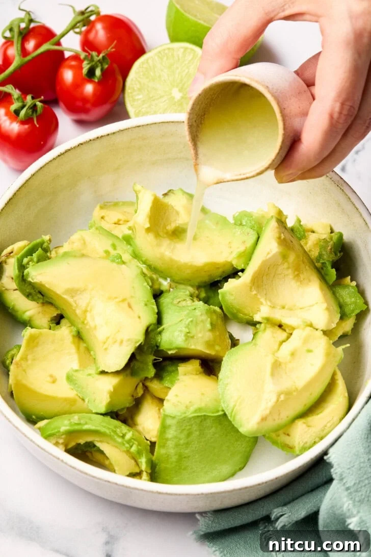 Heavenly Guacamole Perfection 6 Chopped avocados in a bowl with a hand pouring fresh lime juice over them.