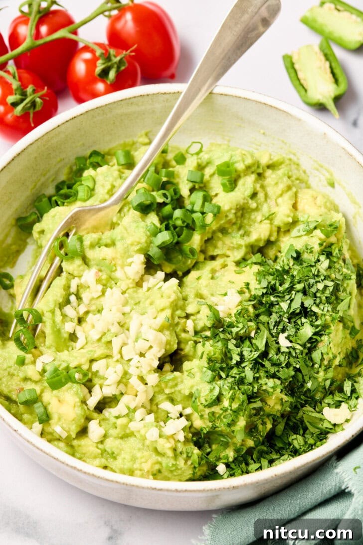 Heavenly Guacamole Perfection 8 Fresh herbs and minced garlic being added to the smashed avocado mixture.