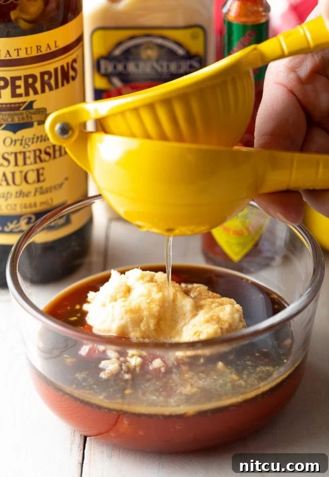 Fresh lemon juice being squeezed directly into the mixing bowl, adding a crucial acidic element to the cocktail sauce.