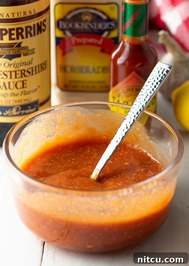 Mixing the ingredients vigorously in a small bowl, ensuring all components are well combined to form a smooth cocktail sauce.