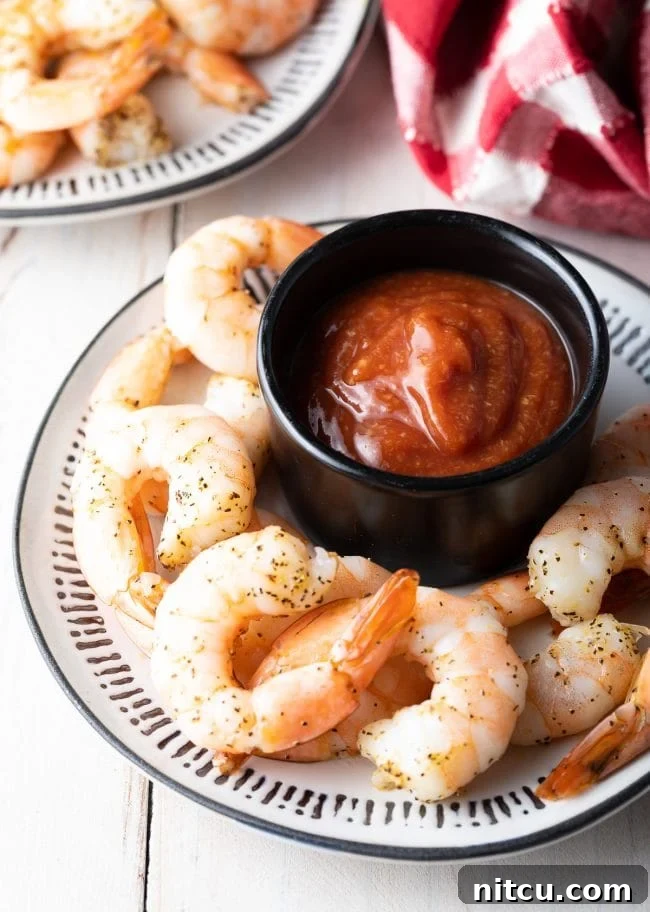 A classic shrimp cocktail presentation on a plate, featuring plump shrimp and a ramekin of homemade cocktail sauce, ready for enjoyment.